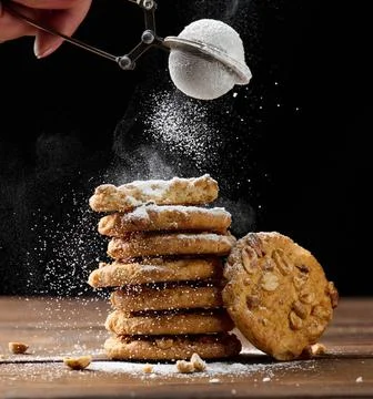 A stack of baked round cookies sprinkled with powdered sugar on a wooden t... Stock Photos
