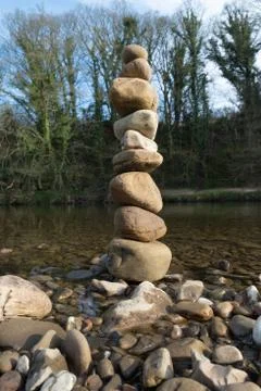 A stack of balanced stones next to a river Stock Photos