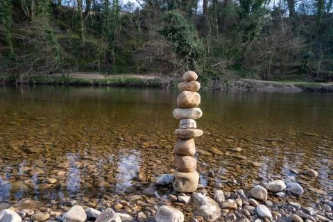 A stack of balancing stones creating rock art next to water Stock Photos