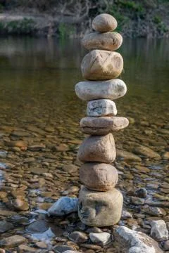 A stack of balancing stones next to water Stock Photos