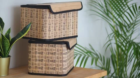 Stack of bamboo storage boxes on wooden shelf with green palm tree plant ba.. Stock Footage 332105498