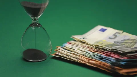 Stack of banknotes with an hourglass that marks the time Stock Footage 146705512
