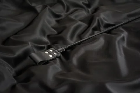 Stack for bdsm games on black silk background. Accessories for adult sexual g Stock Photos