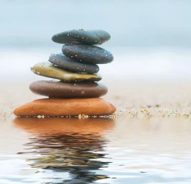 Stack of beach stones on sand. ocean in the background Stock Photos