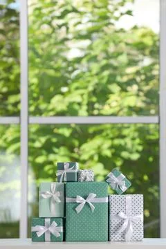 Stack of beautifully wrapped gift boxes on white table  near window. Space fo 스톡 사진
