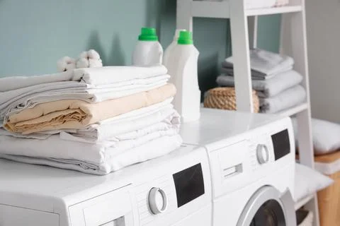Stack of bed sheets with cotton flowers and laundry detergents on washing mac Stock Photos