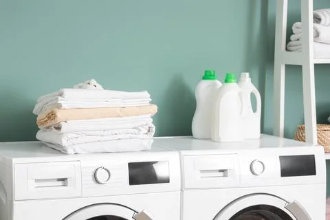 Stack of bed sheets with cotton flowers and laundry detergents on washing mac Stock Photos