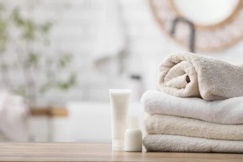 Stack of beige and white towels with toiletries on wooden surface Stock Photos