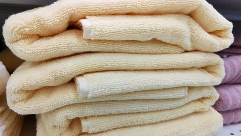 Stack of beige bath towels on shelf of home goods store. Fluffy terry towels Stock Footage 220890945
