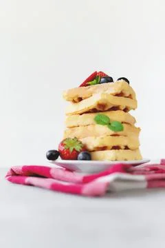 Stack of Belgian waffles, blueberry, strawberry cuts, mint leaf, sugar powder Stock Photos
