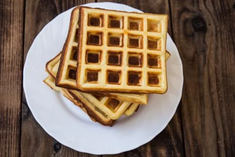 Stack of belgian waffles on a white plate wooden background Stock Photos