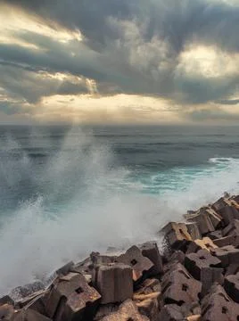 Stack of big concrete cubes forming a breakwater; stormy sea in the backgroun 스톡 사진