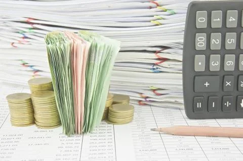 Stack bill between gold coins near brown pencil and calculator Foto stock