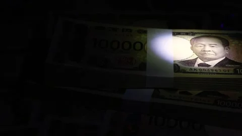 Stack of bills illuminated by a light in the dark Stock Footage 308835443