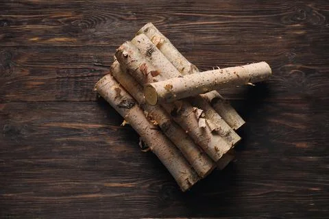 Stack of birch logs on dark wooden background Stock Photos