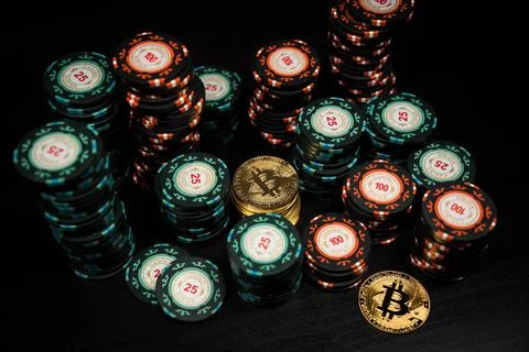 A stack of bitcoin coins on the background of a stack of casino chips Stock Photos