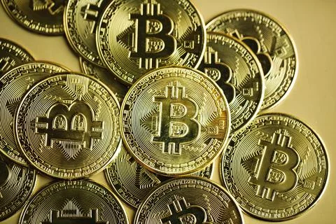 Stack of bitcoins against golden background. Cryptocurrency concept. Stock Photos