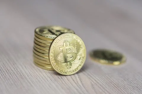 Stack of bitcoins with gold background with a single coin facing the camera in Foto stock