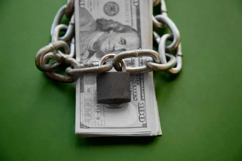A stack of black-and-white hundred-dollar bills and a chain with a lock on th Stock Photos
