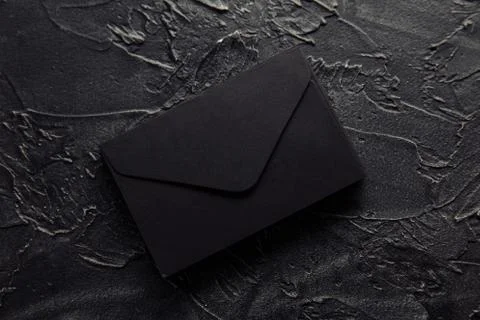 Stack of black envelopes on a dark background. Top view Stock Photos