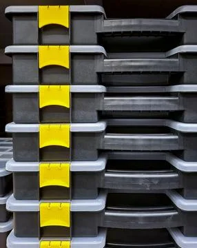 Stack of black plastic toolboxes with yellow latches organized for storage .. Stock Photos