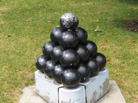 Stack Of Black Round Cannon Balls On Cement Platform Green Grass Stockfoto's