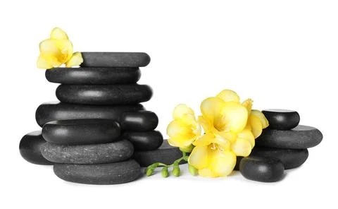 Stack of black spa stones and fresh flowers isolated on white Stockfoto's