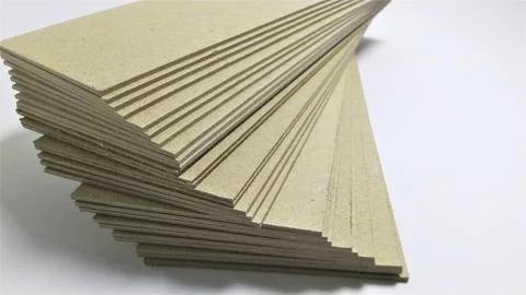 Stack of blank beige cardboard sheets on white background. Stock Photos
