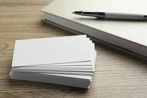 Stack of blank business cards, notebook and pen on wooden table. Mockup for.. Stock Photos