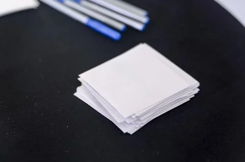 Stack of blank notepads with logo on black table, pens in background Stock Photos
