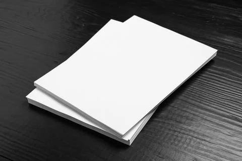 Stack of blank paper sheets for brochure on black wooden background. Mock up Stock Photos