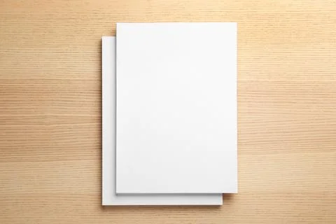 Stack of blank paper sheets for brochure on wooden background, top view. Mock Stockfoto's