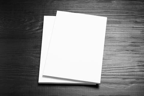 Stack of blank paper sheets for brochure on black wooden background. Mock up 写真素材