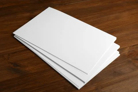 Stack of blank paper sheets on wooden table. Brochure design Foto stock