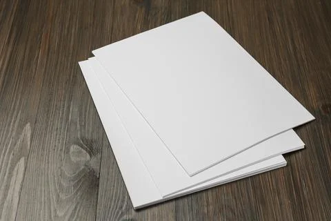 Stack of blank paper sheets on wooden table. Brochure design Stockfoto's