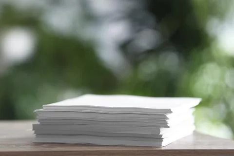 Stack of blank paper on wooden table against blurred background. Space for te 写真素材