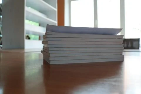 Stack of blank papers on a wooden table in a modern room during daylight 스톡 사진