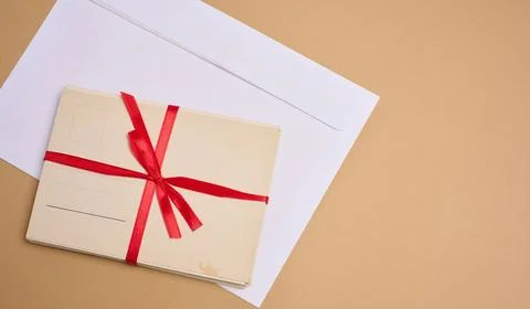 A stack of blank postcards tied with a red ribbon with a bow and an envelop.. 스톡 사진