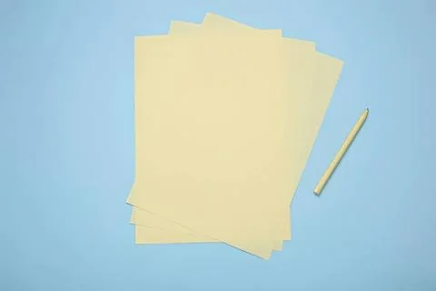 Stack of blank yellow papers with pen on blue background Stock Photos