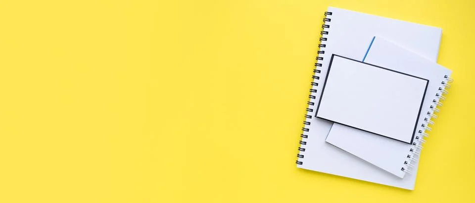 A stack of blocks and notebooks with a spiral. Bright yellow background Stock Photos