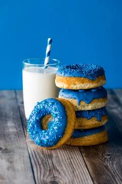A stack of blue chocolate candy dipped donuts with a glass of milk. Stock Photos