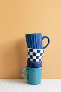 Stack of blue cups on white table. orange wall background Stock Photos