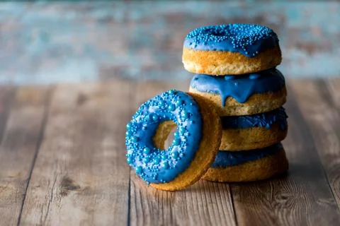 A stack of blue decorated donuts with one leaning in front. 스톡 사진