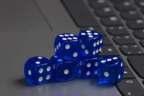 Stack of blue dice on laptop keyboard close up Stock Photos