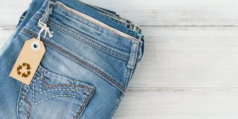 Stack of blue jeans and craft paper tag with Recycling symbol Foto stock