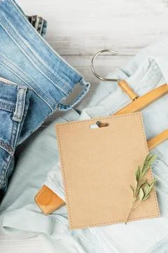 Stack of blue jeans and denim shirt on hanger and empty craft card Foto stock