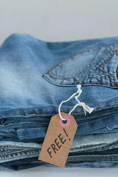Stack of blue jeans and tag with inscription free on white background Foto stock
