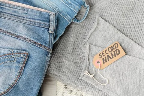 Stack of blue jeans and tag with inscription second hand Stock Photos