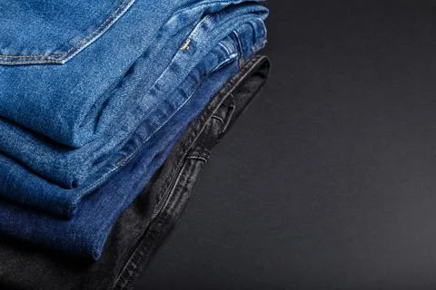 Stack of blue jeans on black background with copy space. Frame made of blue Stock Photos