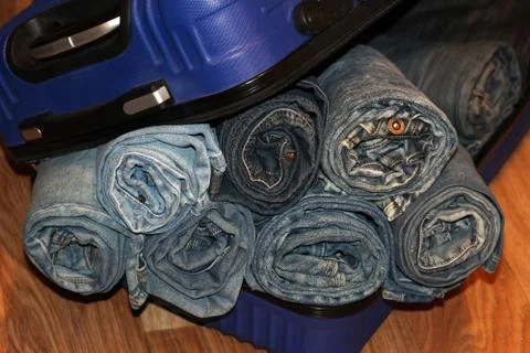 A stack of blue jeans in a blue suitcase Stock Photos